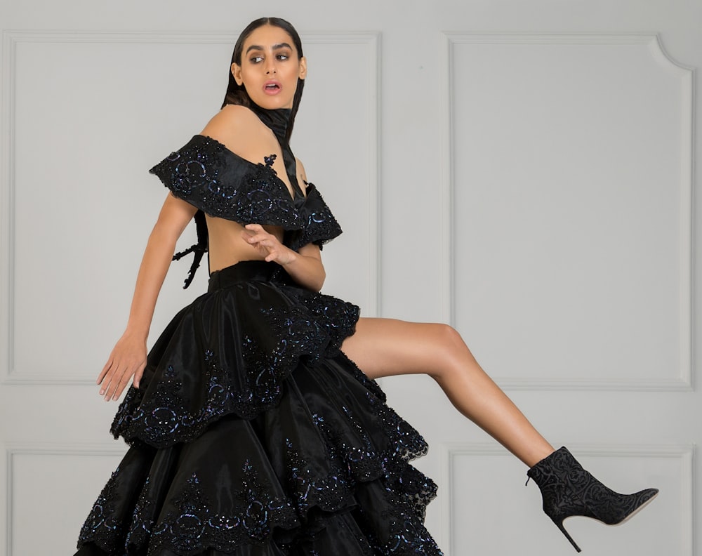 woman in black off-shoulder dress beside wall