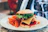 Close-up of a gourmet burger with fresh toppings on a wooden serving board.