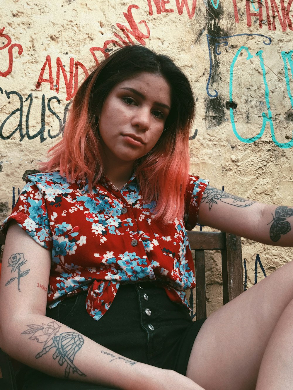 woman in blue and red floral top beside wall