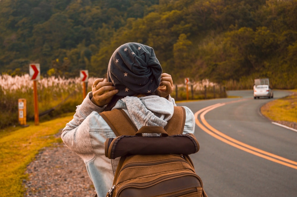 person carrying brown backpack close-up photography