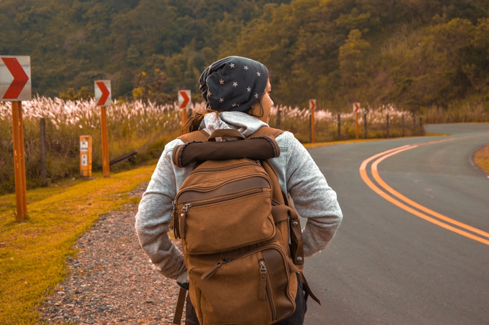 woman with brown backpack beside road