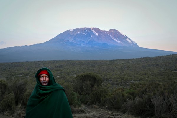 A woman in a green shawl below the mountain — Kilimanjaro, Tanzania