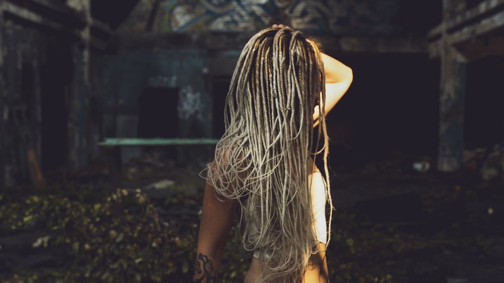 a woman with dreadlocks standing in an abandoned building