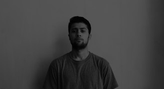 Black and white photo of a person wearing a simple, minimal casual shirt, standing against a plain background.