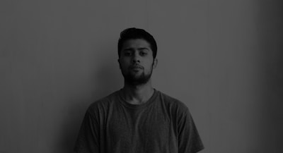 Black and white photo of a person wearing a simple, minimal casual shirt, standing against a plain background.