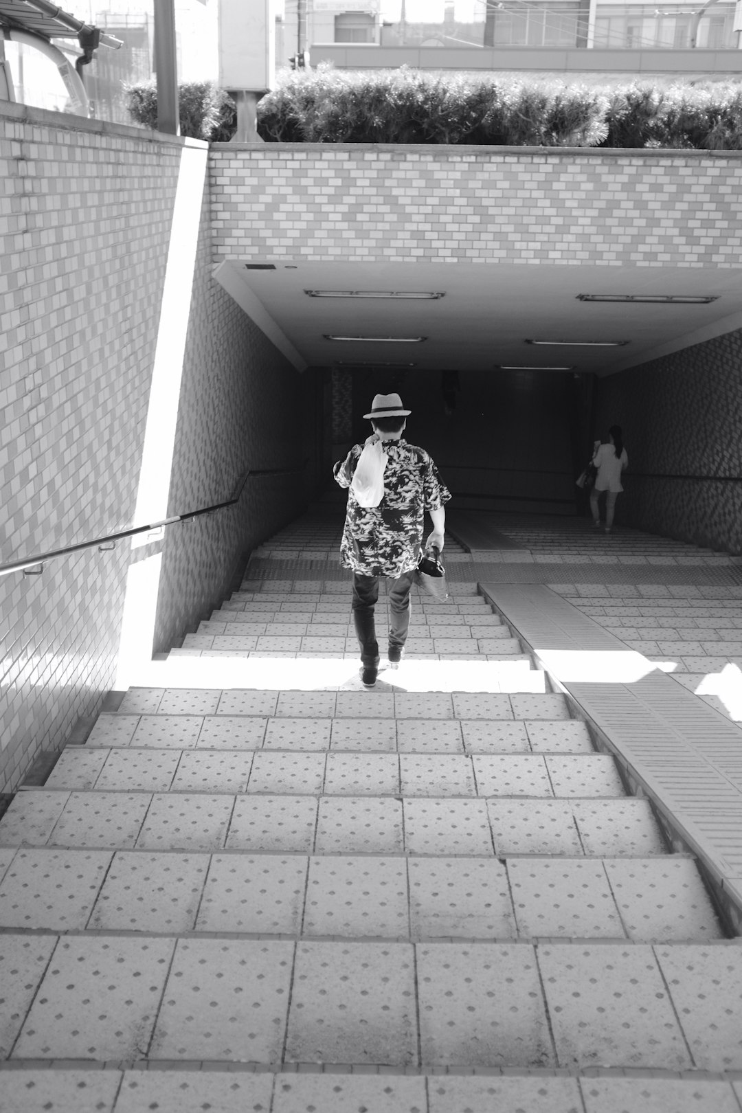 grayscale photography of man walking on concrete stairs