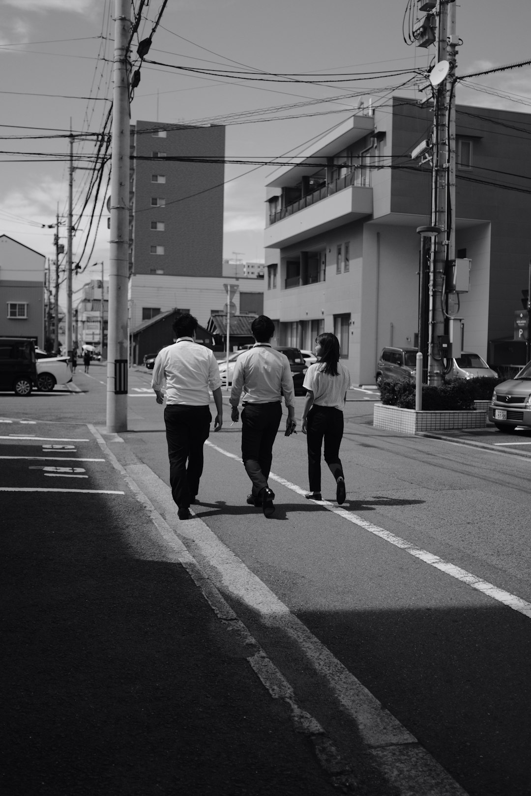grayscale photo of three person standing on road at daytime