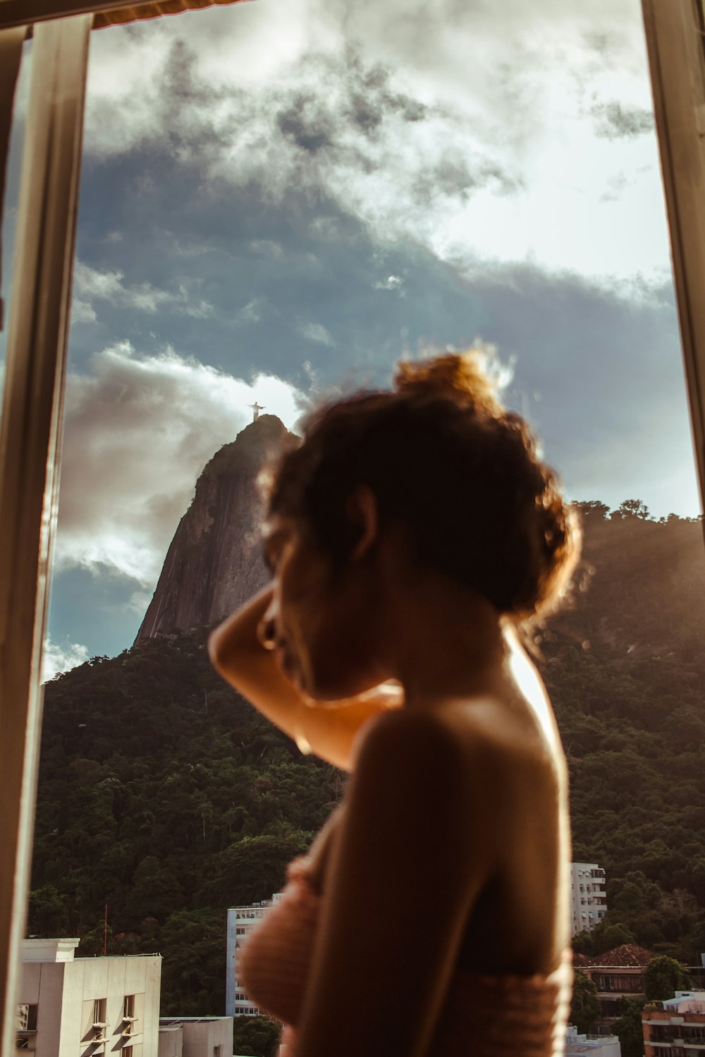 woman holding her hair while standing near glass window