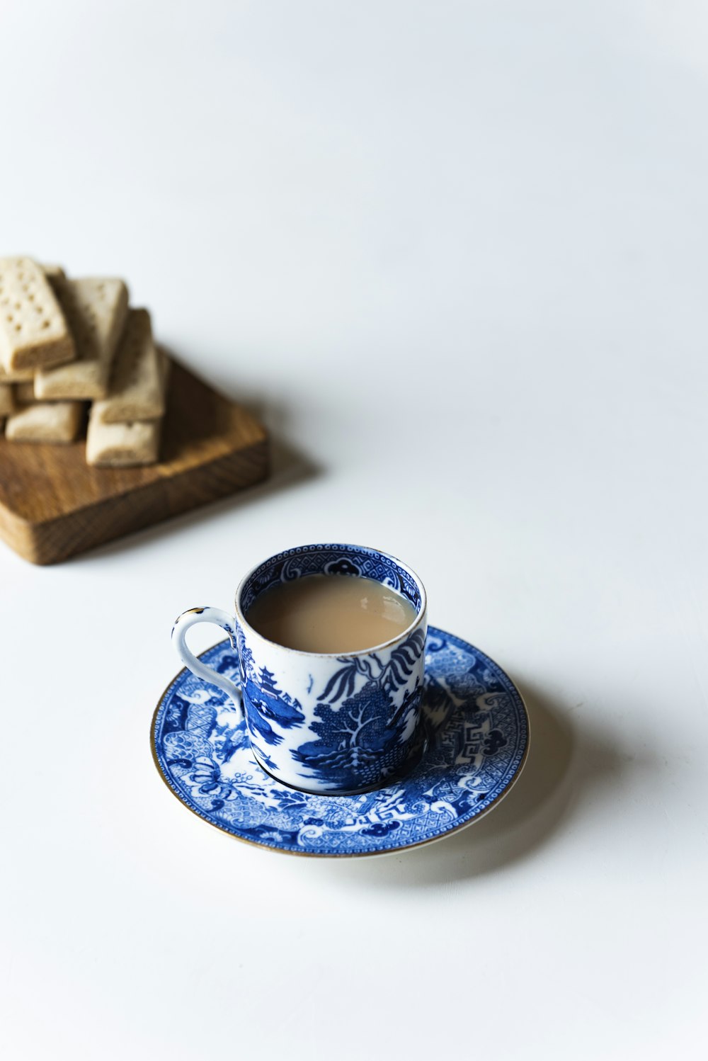 white and blue ceramic mug on saucr