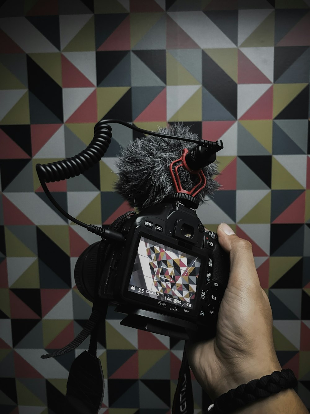 person holds DSLR camera with stereo recording cardioid microphone