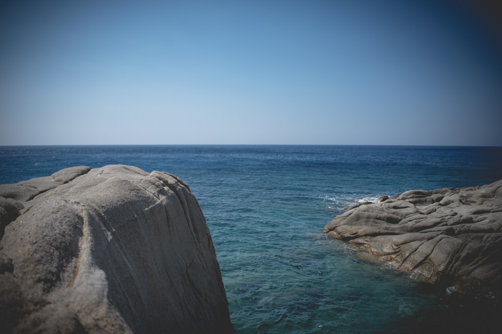 gray rock formation beside blue sea under blue sky during daytime