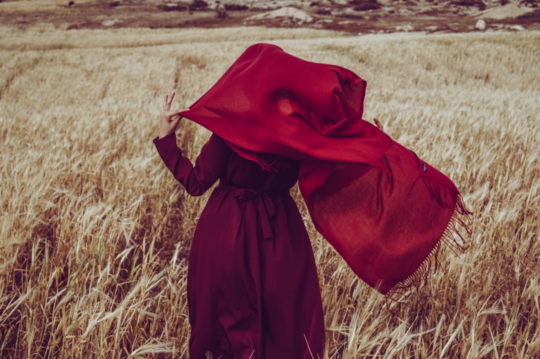 person wearing red scarf on brown grass field