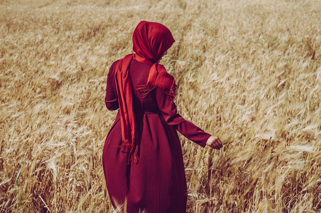 woman wears abaya dress and headscarf while walking on the grass