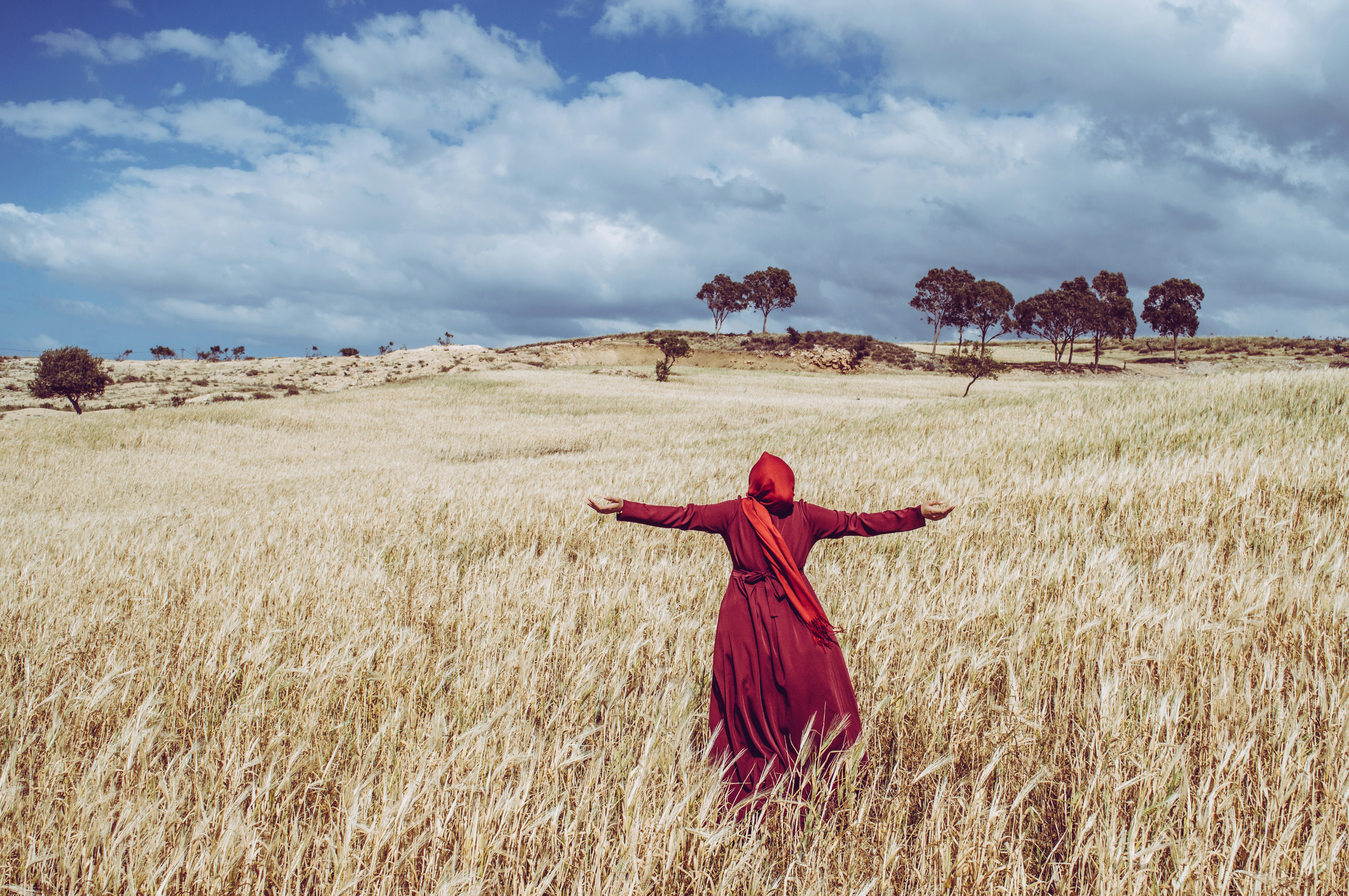woman wearing red dress standing on brown grass