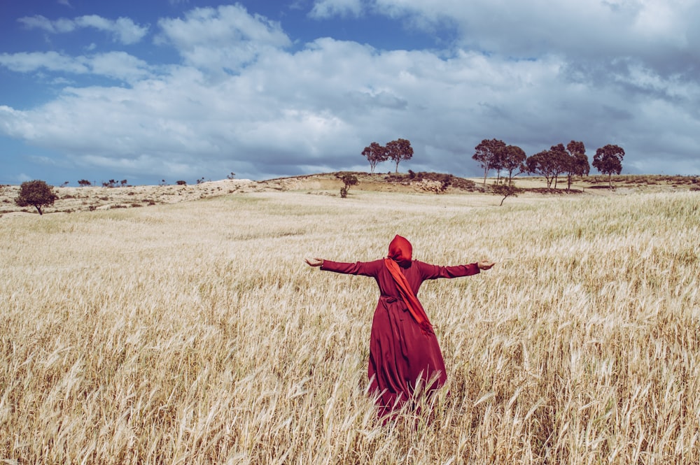 woman wearing red dress standing on brown grass
