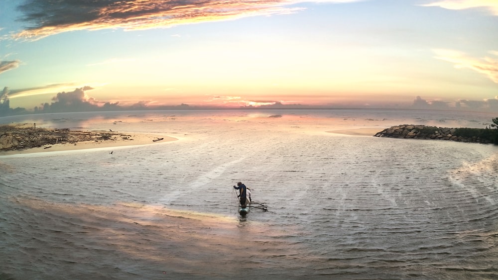 a man standing on a surfboard in the middle of a body of water