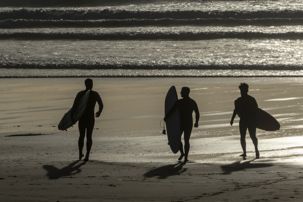 tre persone che trasportano tavole da surf