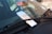 A parking ticket is tucked under the windshield wiper of a car. The background shows a red car parked in an outdoor setting.