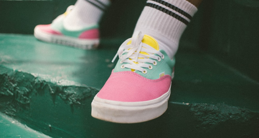 person wearing white and black socks and pink-yellow-and-green low-top sneakers