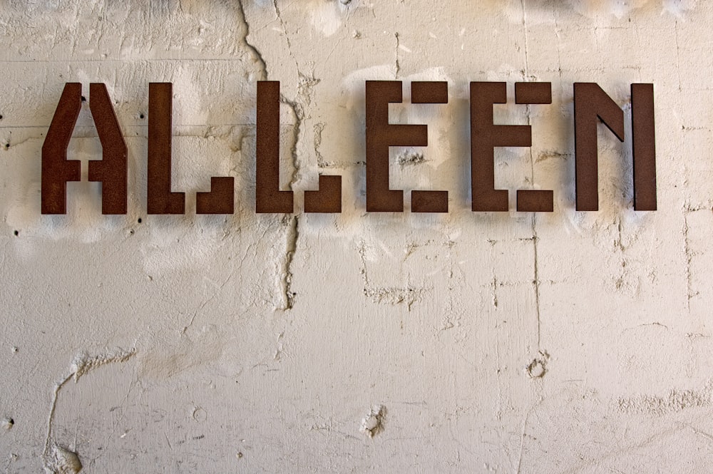 Alleen signage mounted on white wall