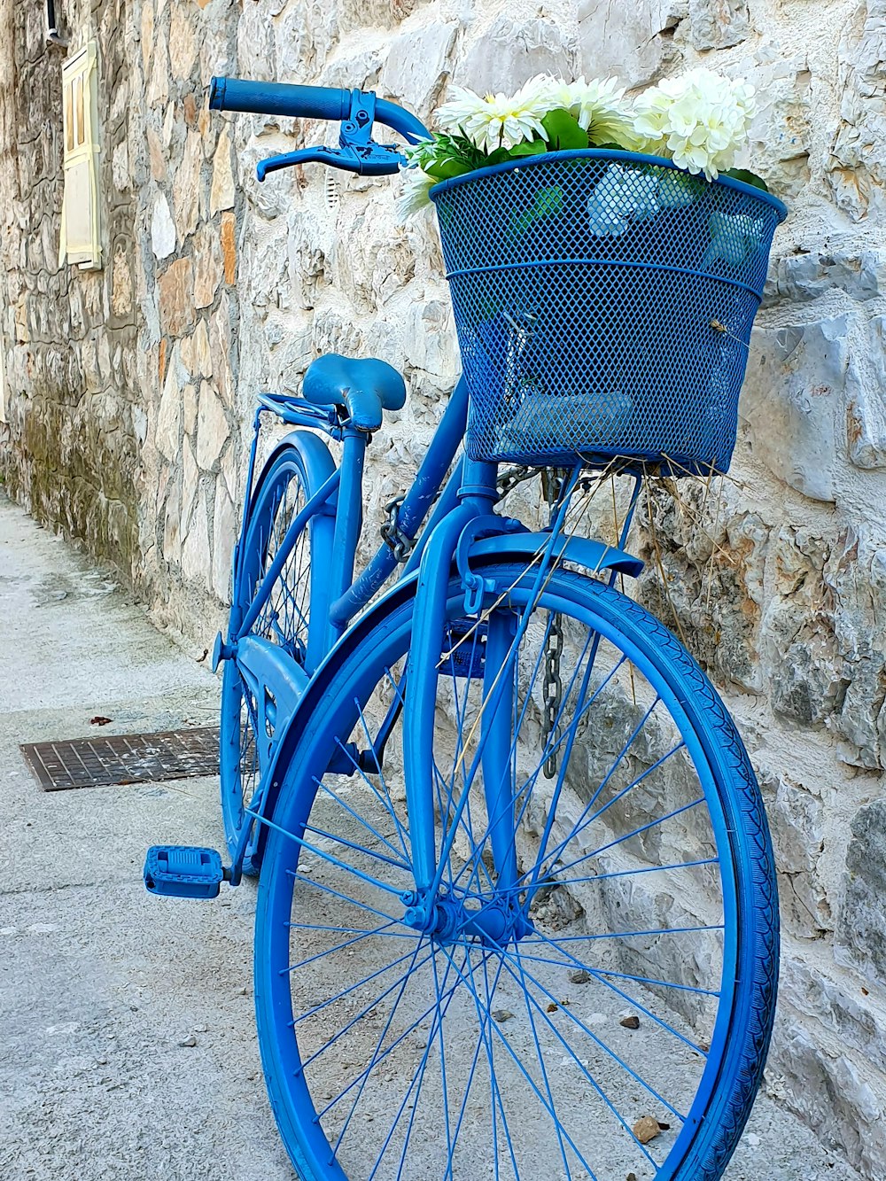 blue commuter bike with white flowers inside basket