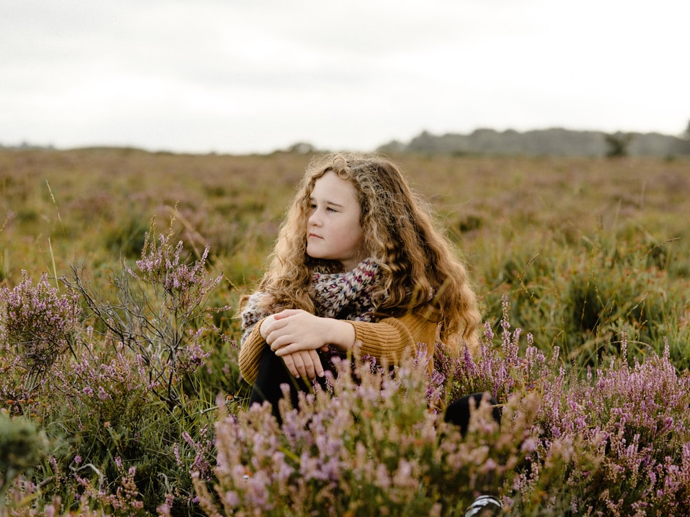 a woman sitting in a field of flowers