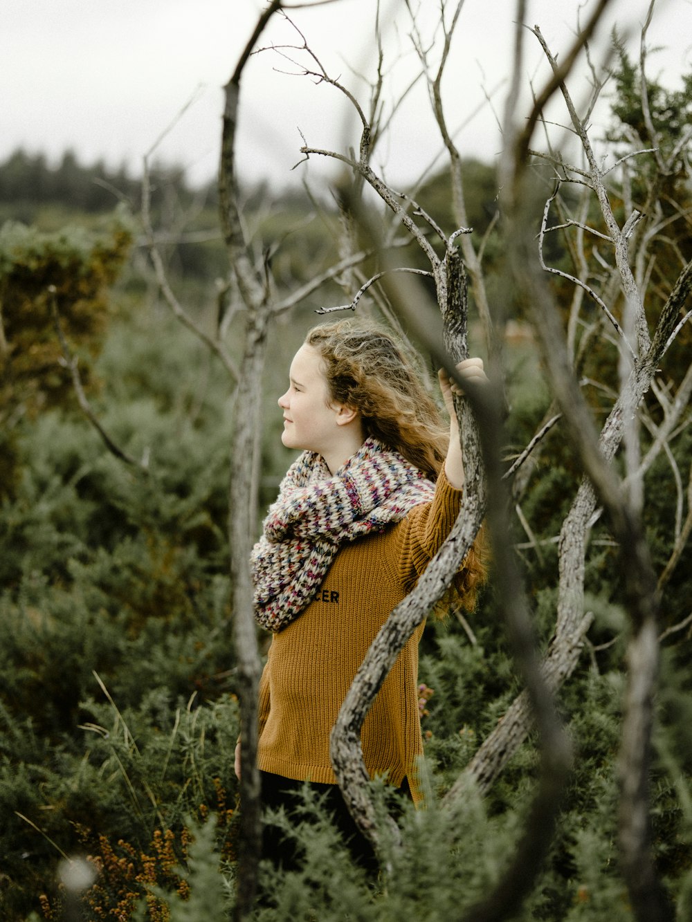 a woman standing in a forest with a snake wrapped around her neck