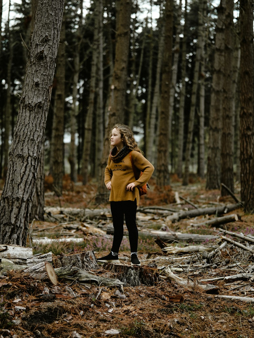 a young girl standing in the middle of a forest