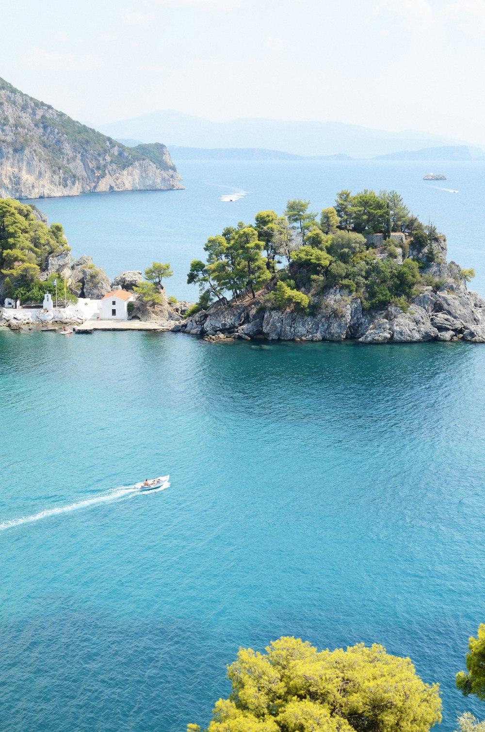 islet with trees beside mountain during daytime