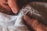 Close-up of a tailor's hands stitching a fine suit jacket.