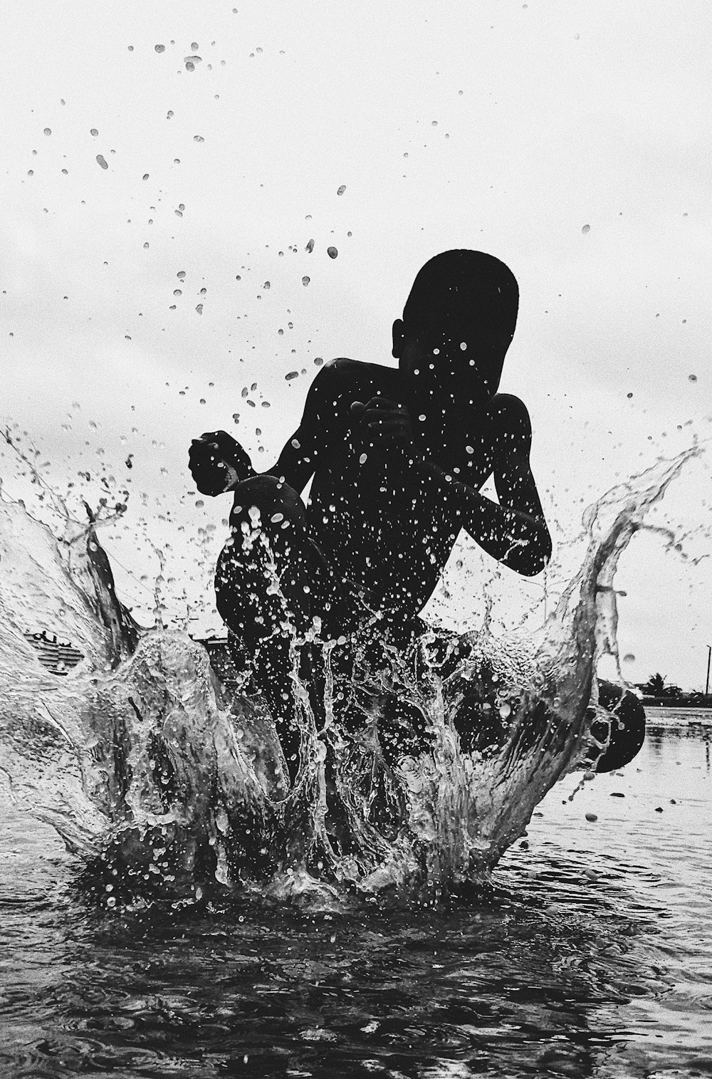 grayscale photography of person sitting near body of water