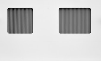 Two rectangular sections with vertical black and gray lines set against a white background. The lines create a metallic, grid-like appearance, suggesting a minimalist and industrial design.