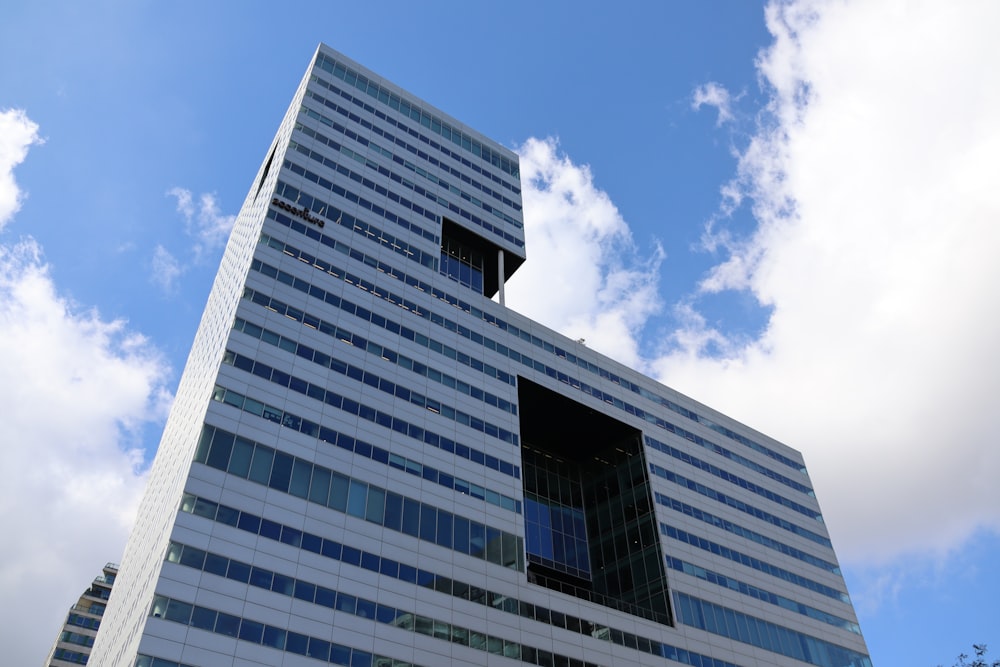 Photographie en plongée d’un immeuble de grande hauteur sous un ciel bleu et blanc pendant la journée