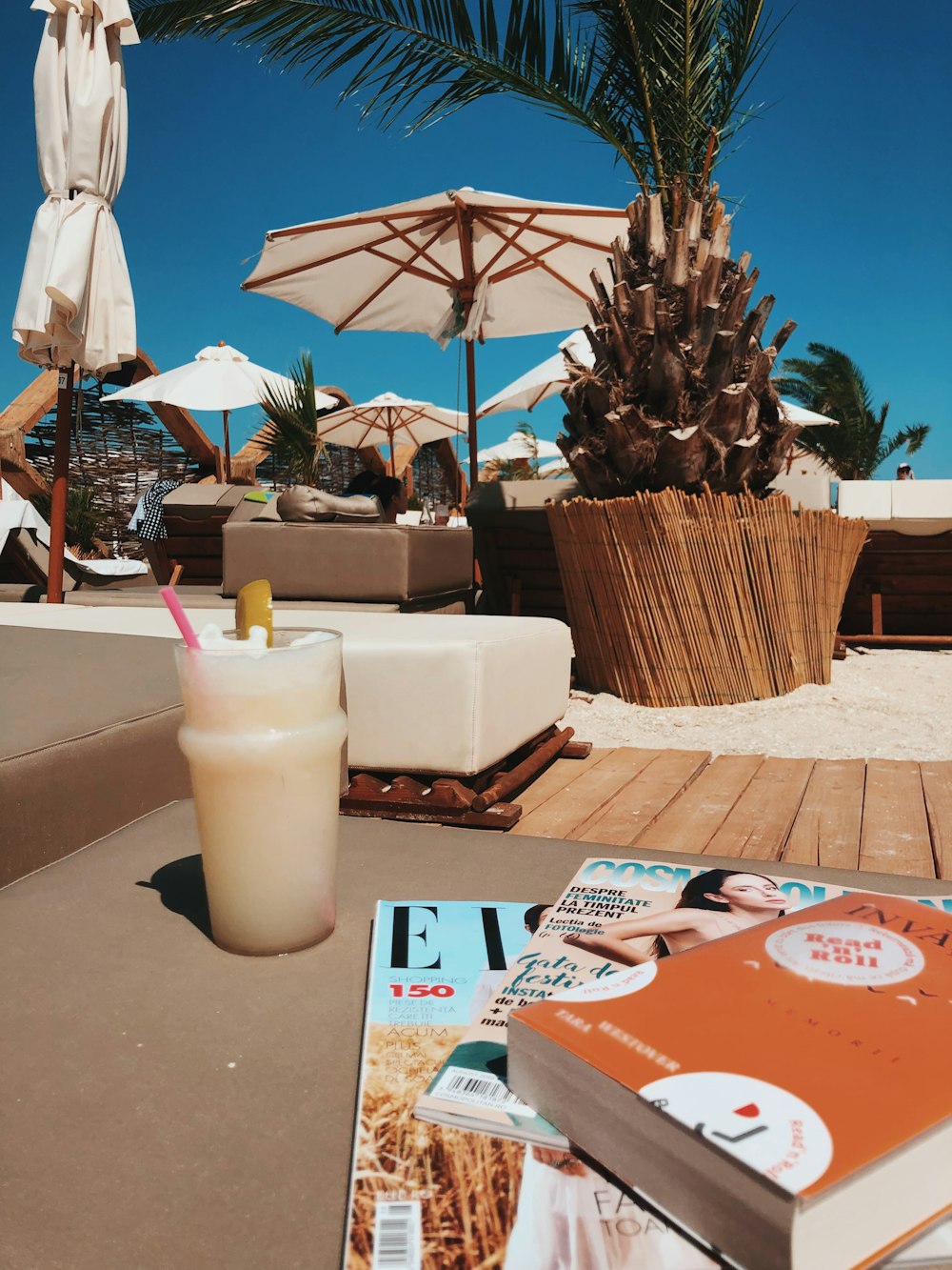 glass of cold beverage beside magazines on cloudy day