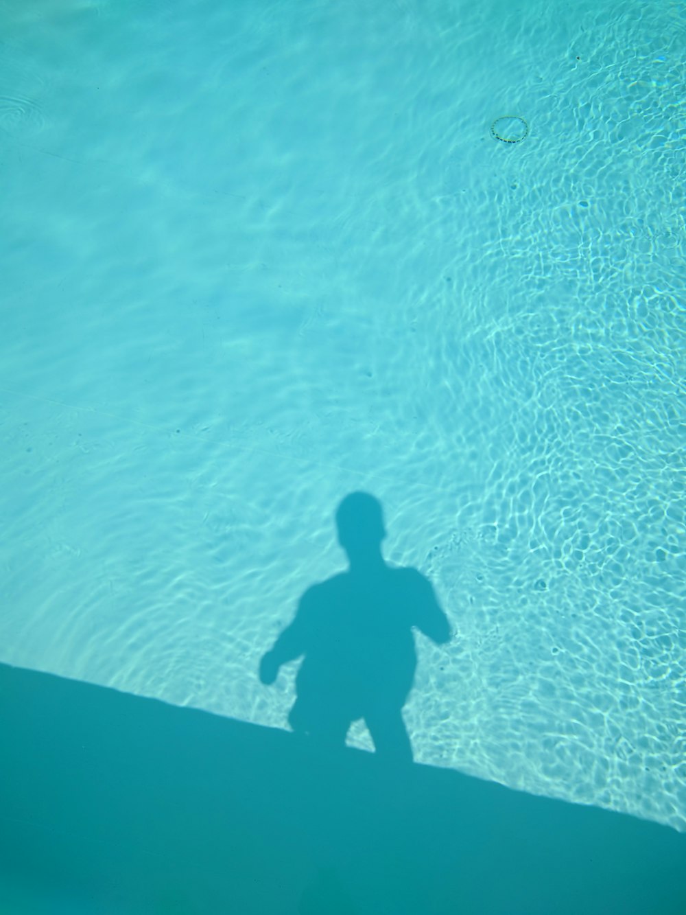 uma sombra de uma pessoa em pé em uma piscina