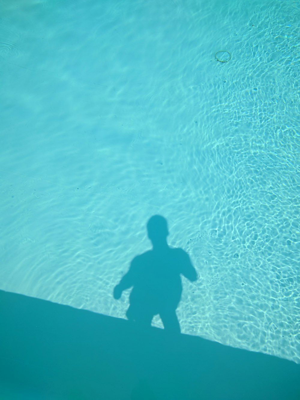 ein Schatten einer Person, die in einem Pool steht