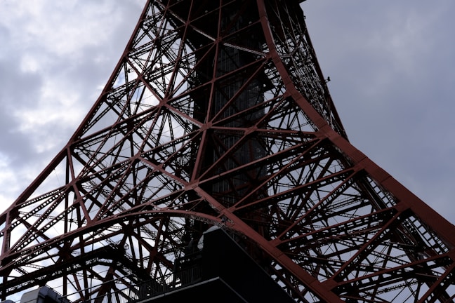 A close-up of steel beams being welded on a large construction site under a cloudy sky.
