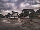 A bus arriving at a busy station with passengers waiting under dark skies.