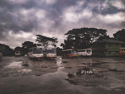 A bus arriving at a busy station with passengers waiting under dark skies.