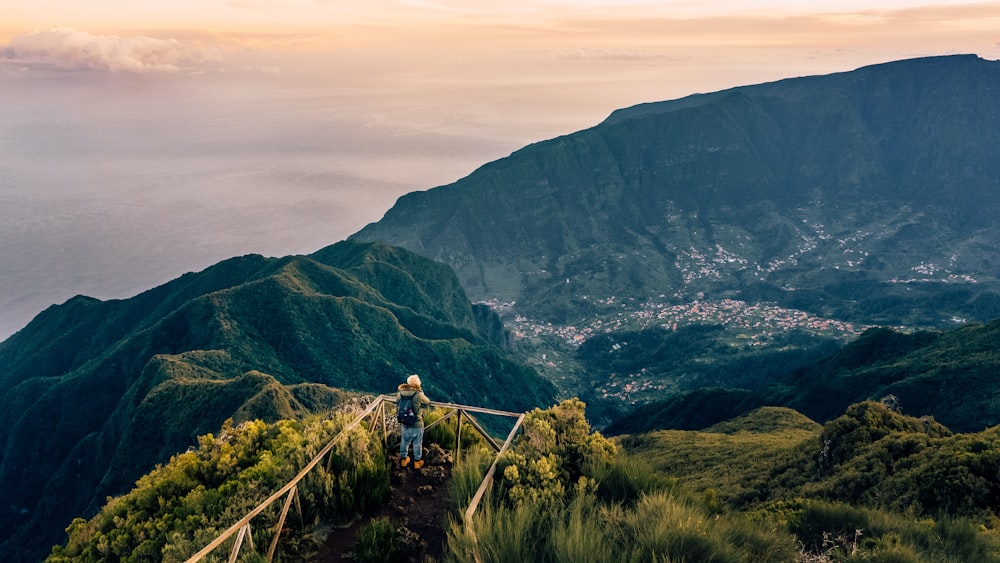 aerial photography of person on cliff overlooking mountains