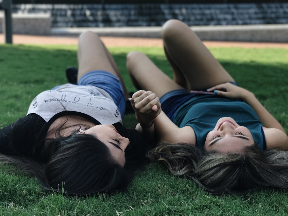 two woman lying on grass