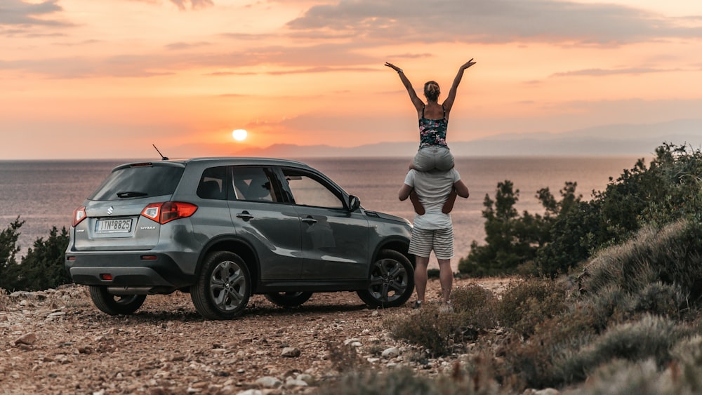 a couple of people standing on top of a car