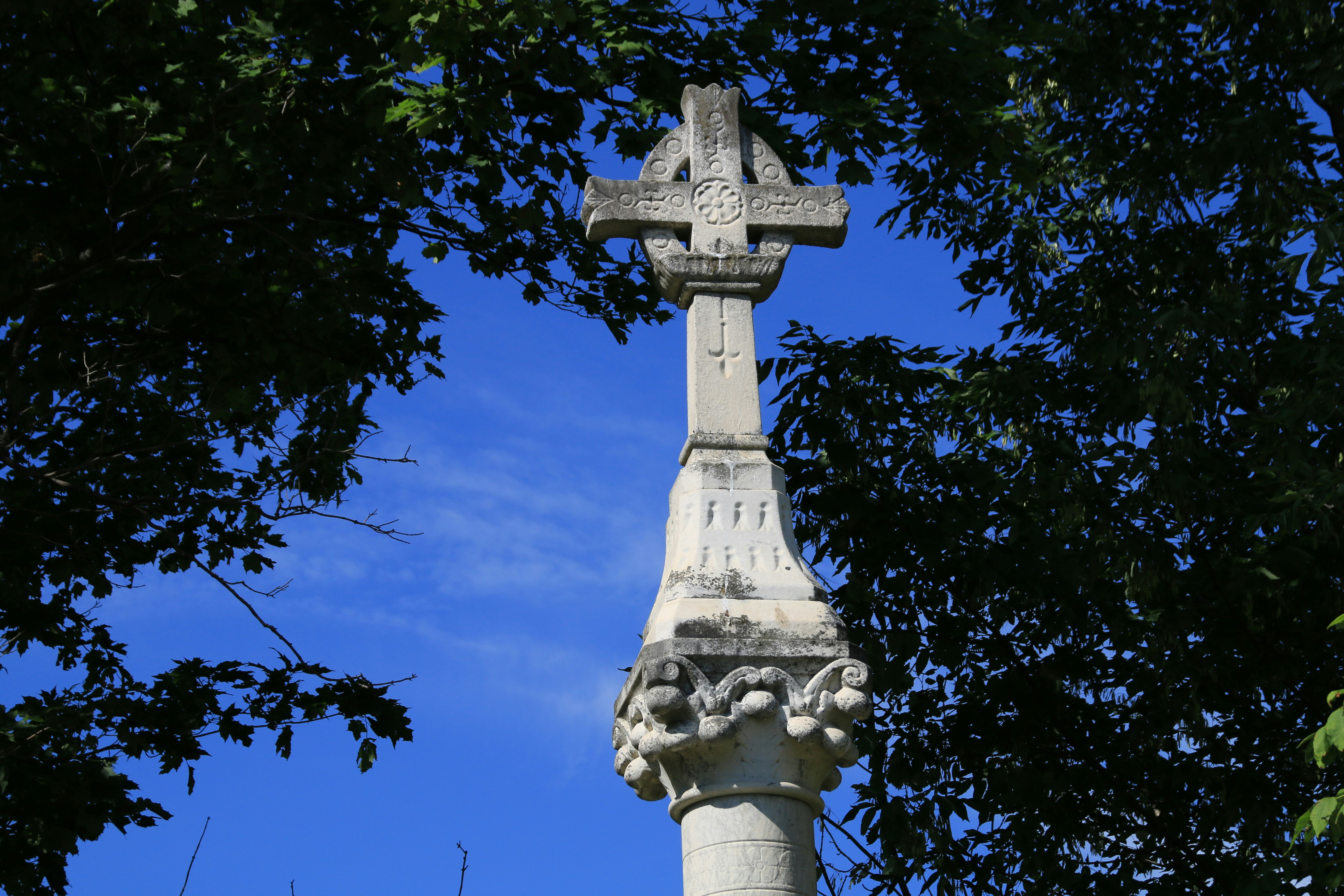 gray concrete cross statue near trees
