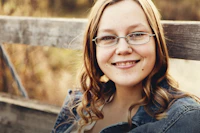 woman with eyeglasses sits on bench