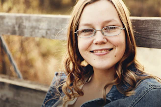 woman with eyeglasses sits on bench