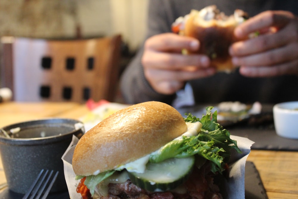 a person sitting at a table with a sandwich in front of them