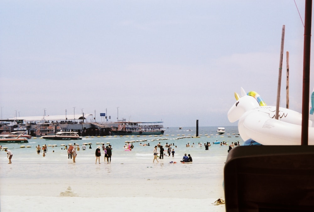 a crowded beach with people and boats in the water