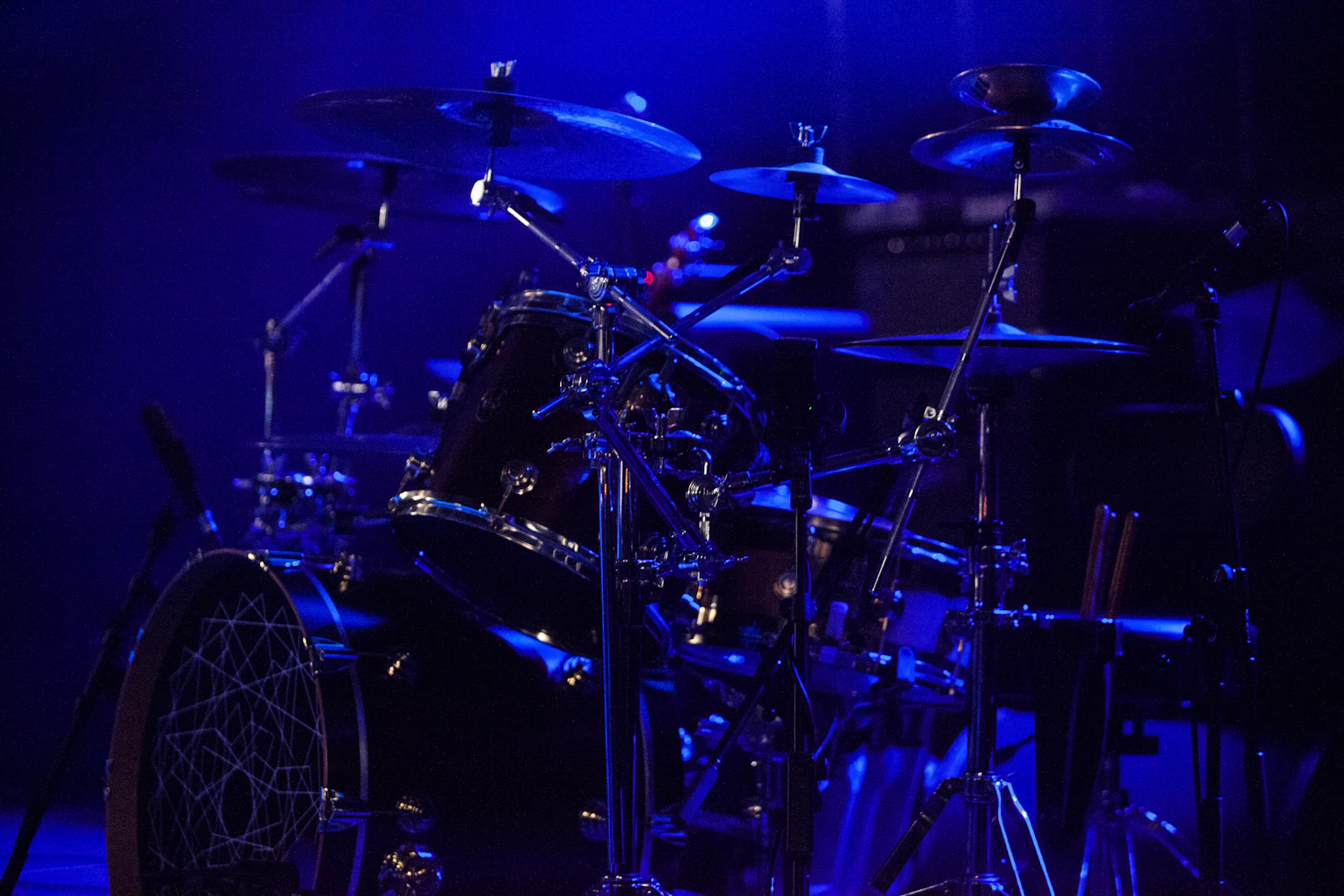 A drum kit lit blue on an empty stage before doors