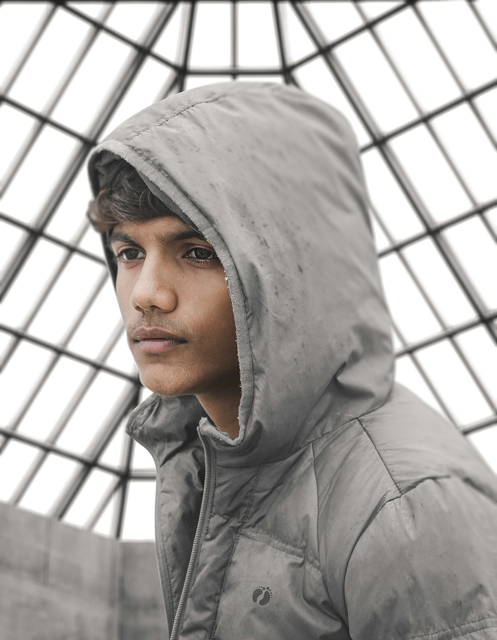 a young man in a hooded jacket looking at the camera