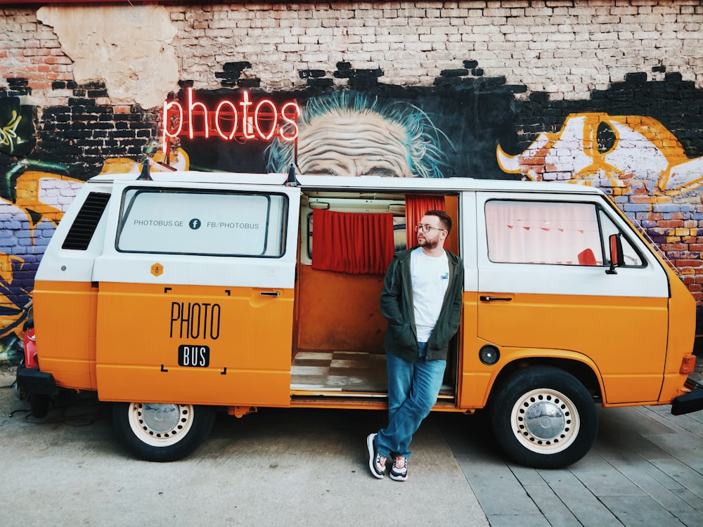 man leaning on orange van